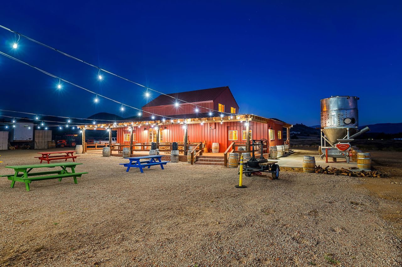 The red barn at blue hour, strung with lights above picnic tables