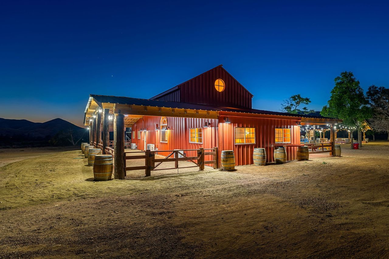 The red barn from outside at dusk, mountains on the horizon