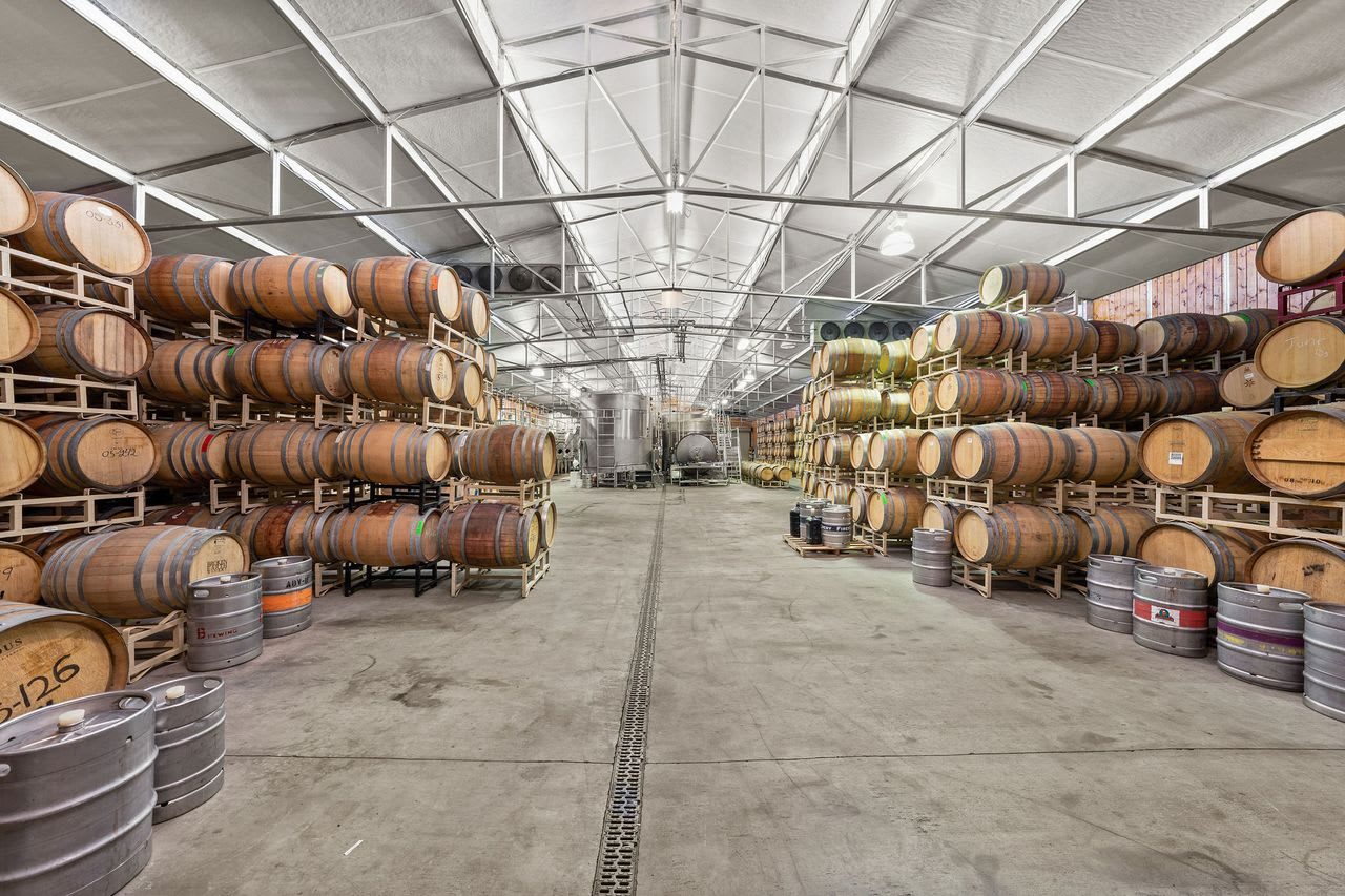 The barrel warehouse, stacked with rows of oak barrels under a steel roof