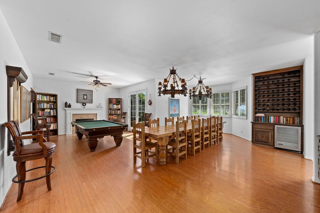 The game room, with a pool table, a long dining table and bookshelves