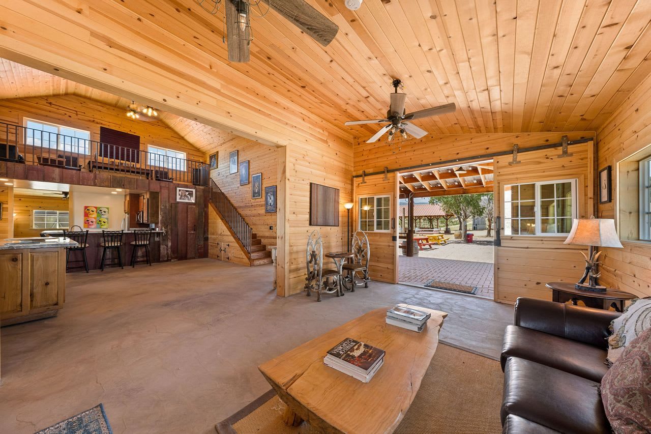 Inside the two-story barn: knotty pine walls, open beams and a stair to the loft